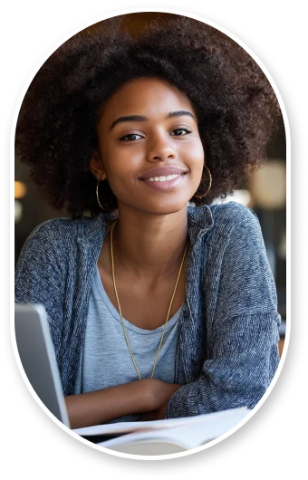 A single graduate student at a desk in modern library, working on laptop with good posture